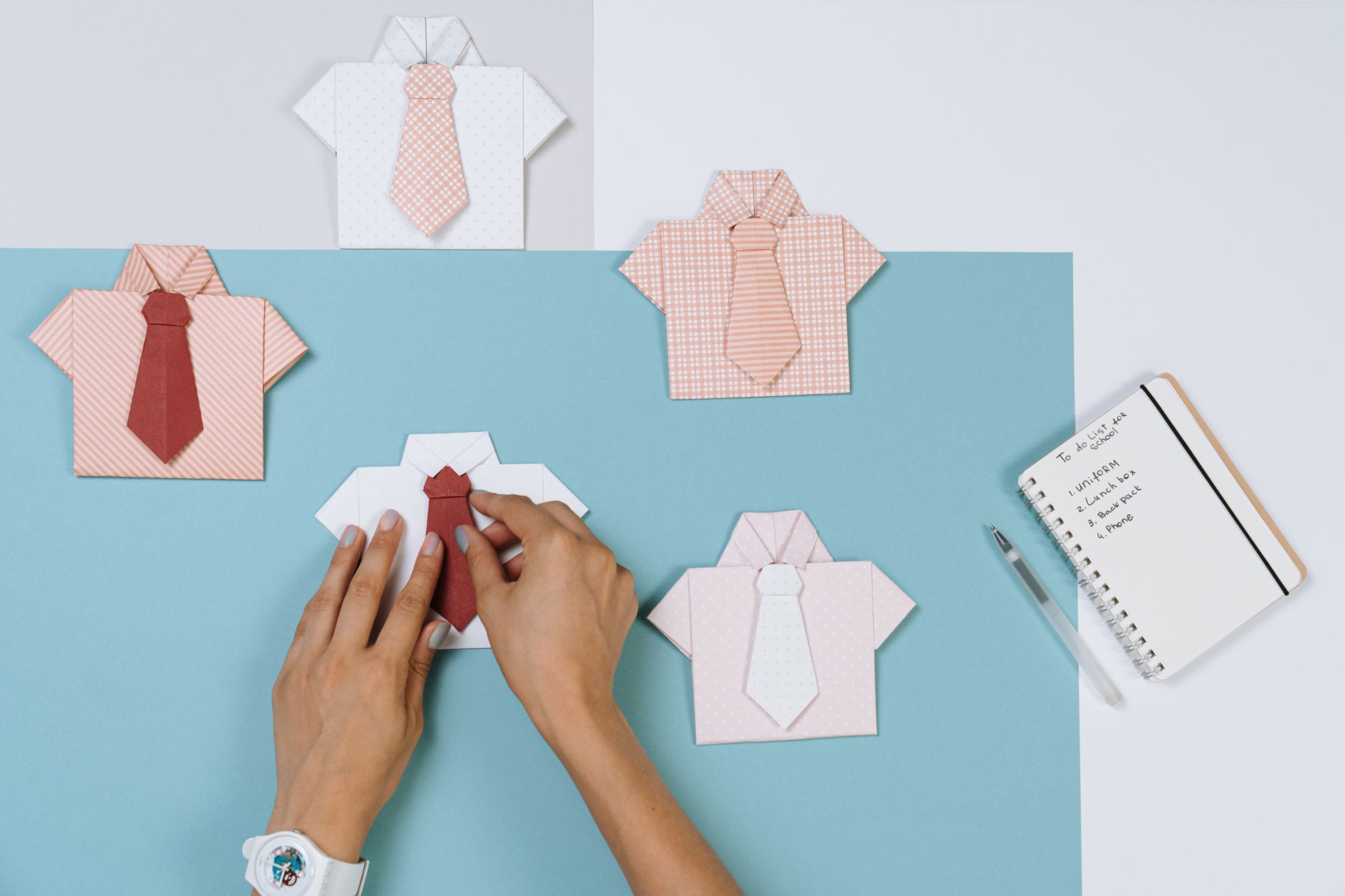 Płaskie origami koszule z krawatami obok listy zadań na biurku