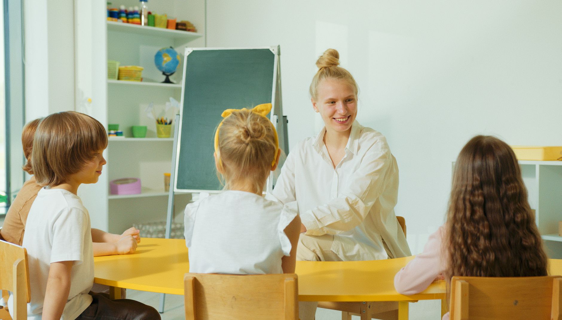 Nauczycielka rozmawia z przedszkolakami w kolorowej sali